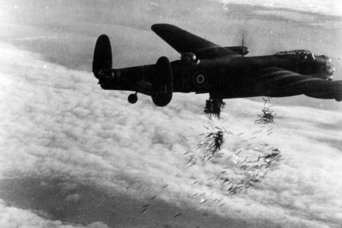 Still from film shot by the RAF Film Production Unit during Operation HURRICANE. Avro Lancaster B.I, NG128/SR-B, of 101 Squadron RAF, piloted by Warrant Officer RB Tibbs, releases bundles of 'Window' over the target during a special daylight raid on Duisburg on 14 October 1944. Over 2,000 sorties were dispatched to the city during 14-15 October 1944, in order to to demonstrate Bomber Command's overwhelming superiority in German skies. Note the large aerials on top of the Lancaster's fuselage, indicating that the aircraft is carrying 'Airborne Cigar' (ABC), a jamming device which disrupted enemy radio telephone channels.
