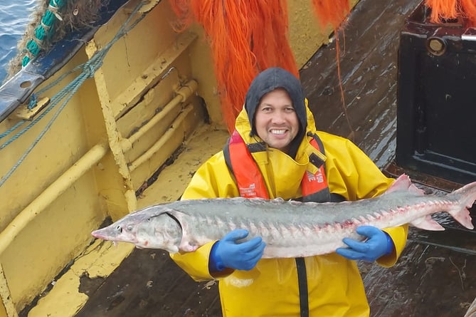 Sean Beck posing with the sturgeon he caught shortly before it was released back into the sea